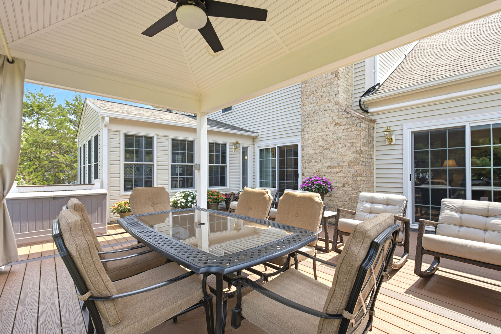 Covered outdoor pavilion with dining and lounge seating overlooking the yard